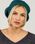 A woman wearing a green Merinosilk beret hat.