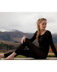 Woman in black outfit sitting outdoors with mountains in the background