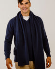 Man wearing a navy blue cardigan and scarf on a plain background