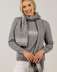 Woman wearing a gray sweater and patterned scarf against a plain background