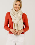 Woman wearing a red sweater and white scarf against a plain background
