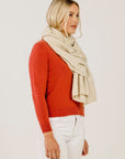 Woman wearing a red sweater and beige scarf on a plain background