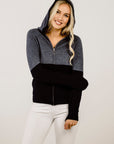 Woman wearing a grey and black hoodie on a plain background
