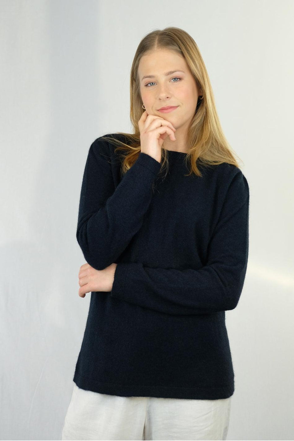 Woman wearing a Ink merino silk sweater with white pants
