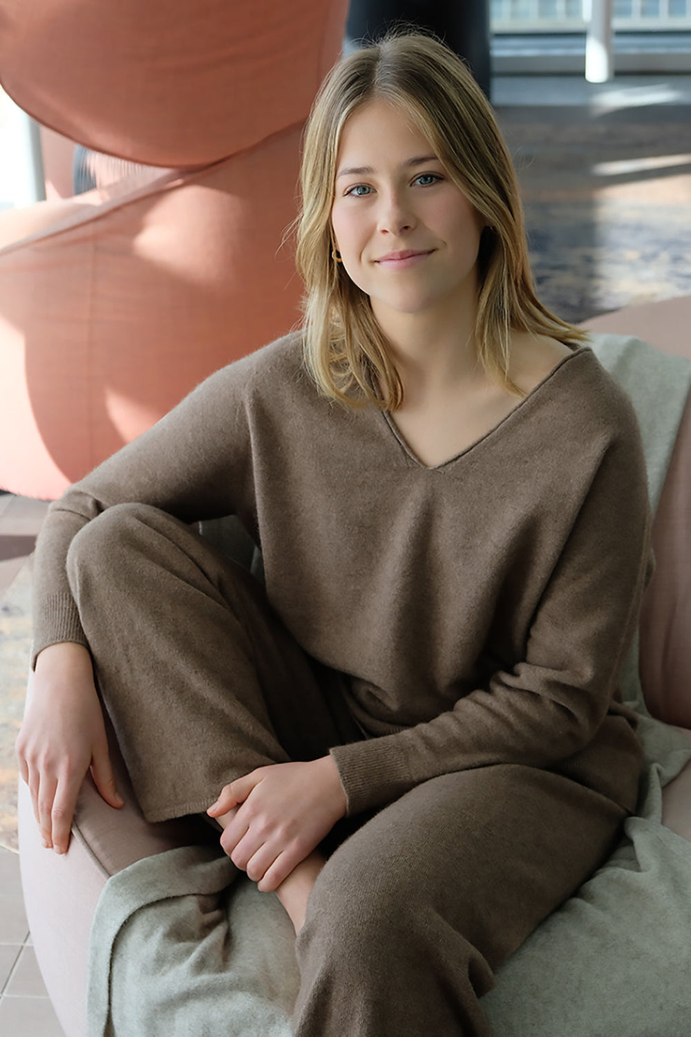 Woman in a brown outfit sitting on a couch in a modern indoor setting