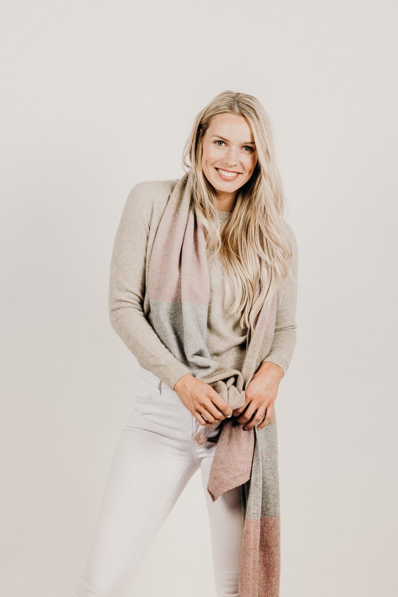 Woman wearing a light gray sweater and scarf against a plain background