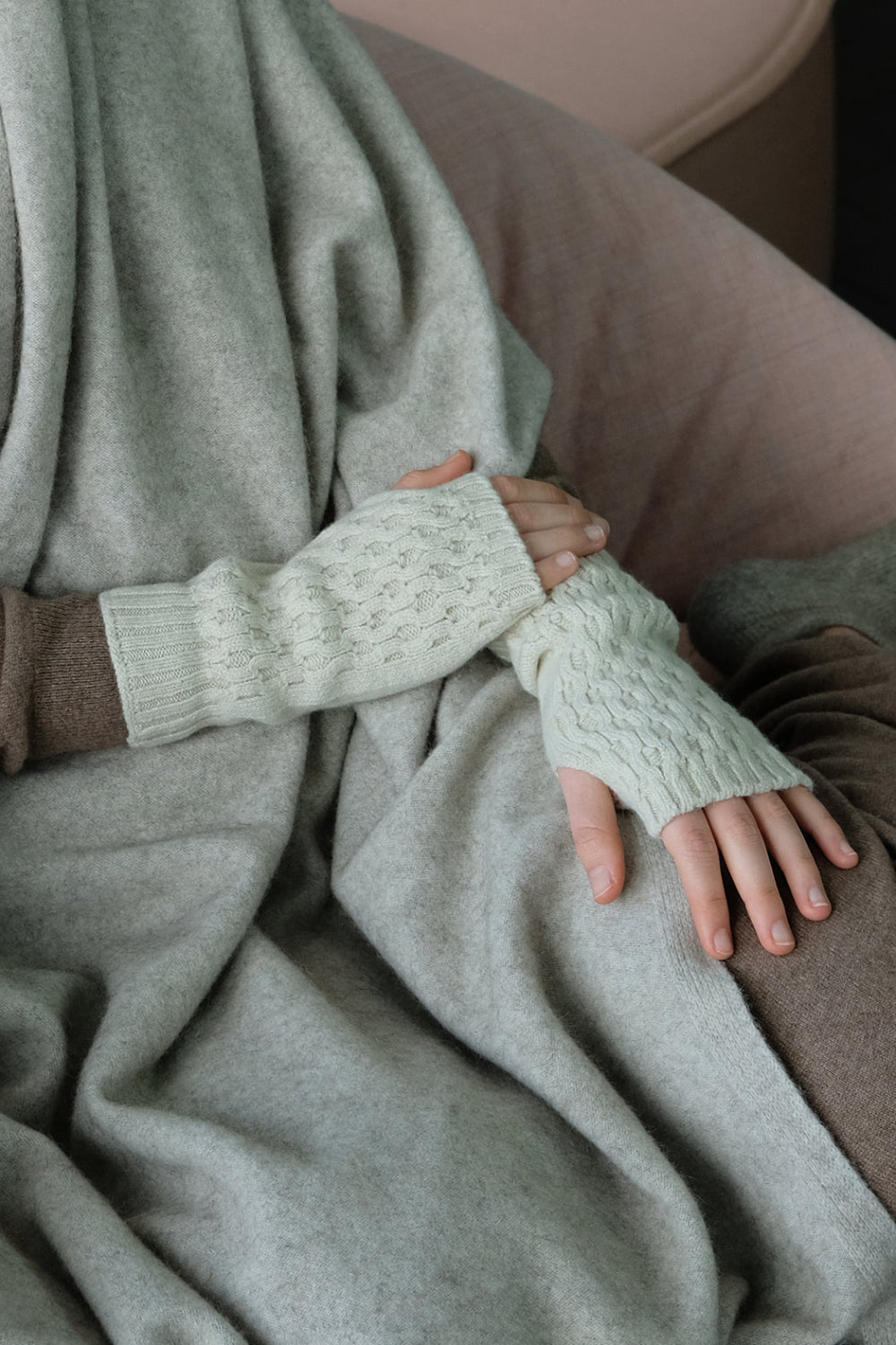 Person wearing white wrist warmer sitting on a beige couch.