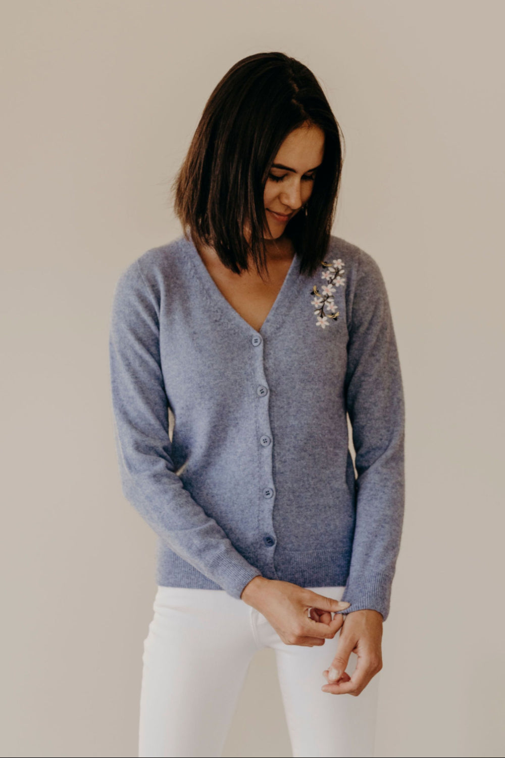 Woman wearing a blue cardigan with a floral pattern against a plain background
