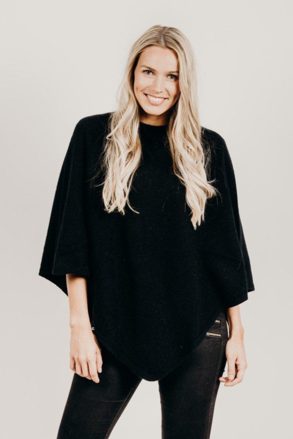 Woman wearing a black poncho and black pants