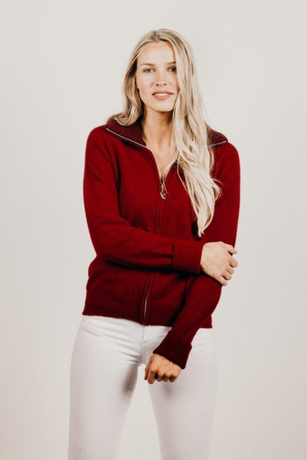 Woman wearing a red jacket with a zipper on a plain background