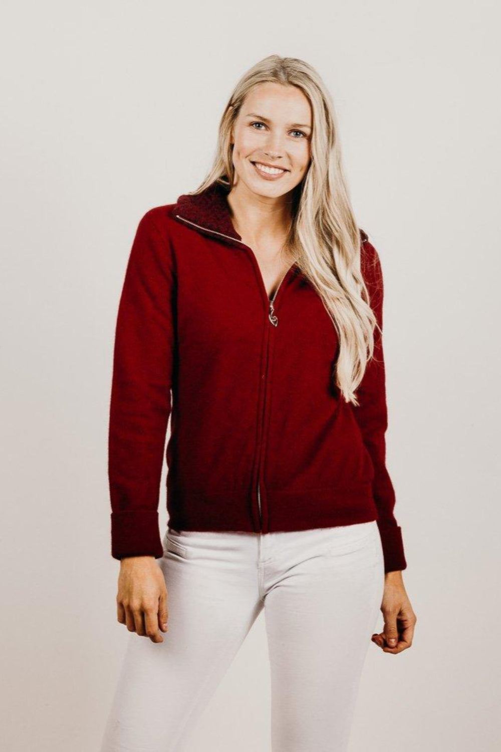 Woman wearing a red zip jacket against a plain background