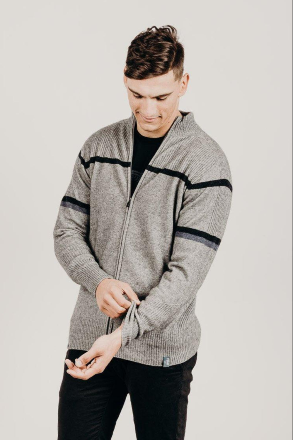 Man wearing a gray zip-up hoodie with black accents on a light gray background