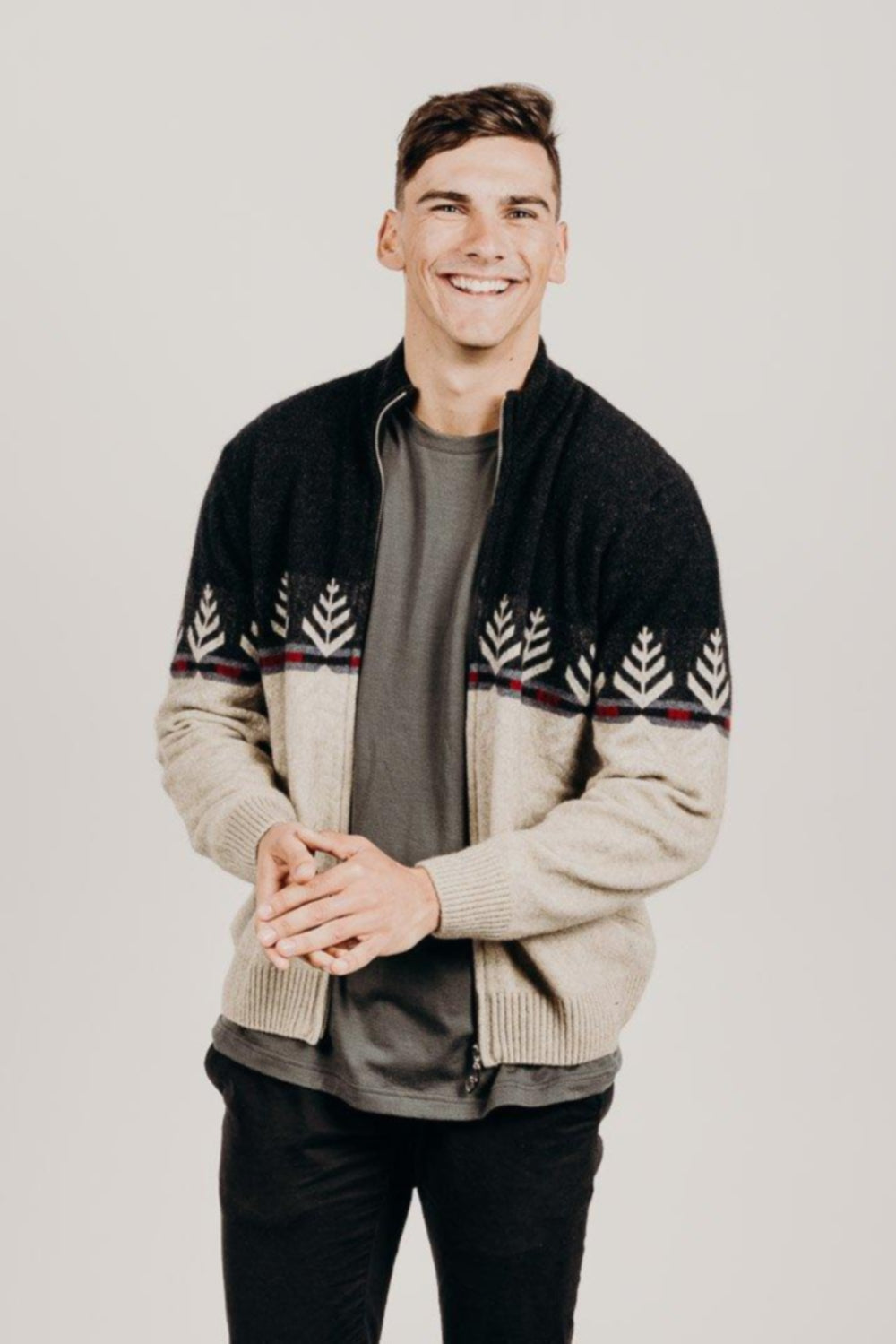 A person standing against a plain background, wearing a Merinosilk Silver Fern Jacket with full zip and ribbed hems, featuring a unique Silver Fern print.