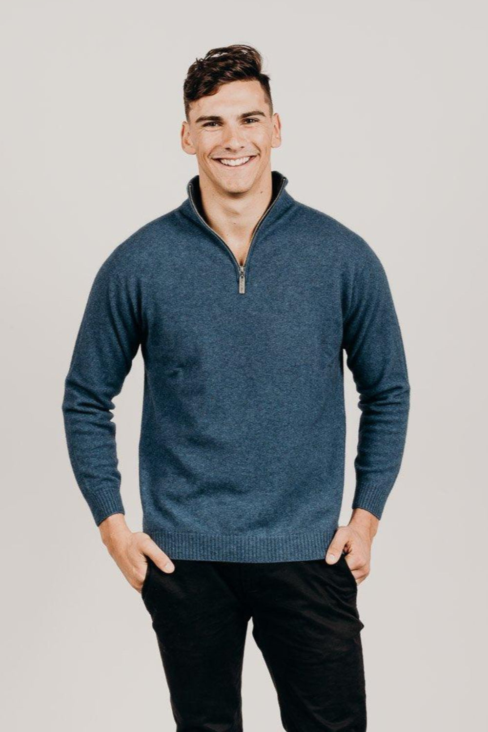 Man wearing a blue sweater with a zipper on a plain background