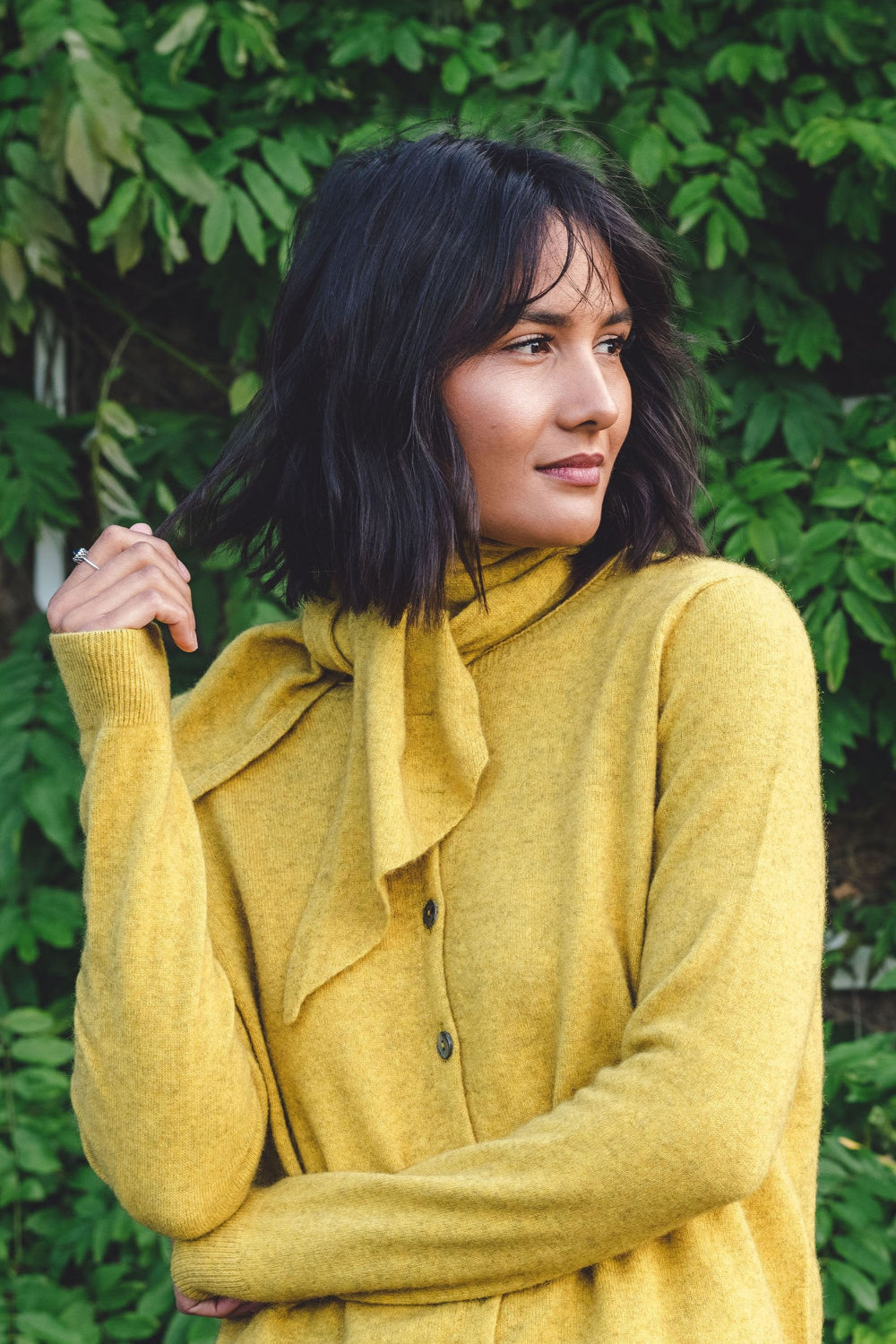 Woman wearing a yellow sweater with a green leafy background