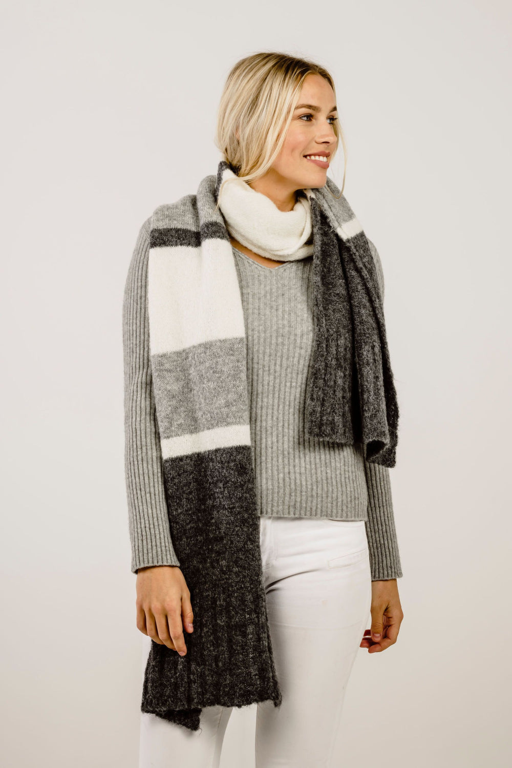 Woman wearing a gray and black striped scarf with a white background