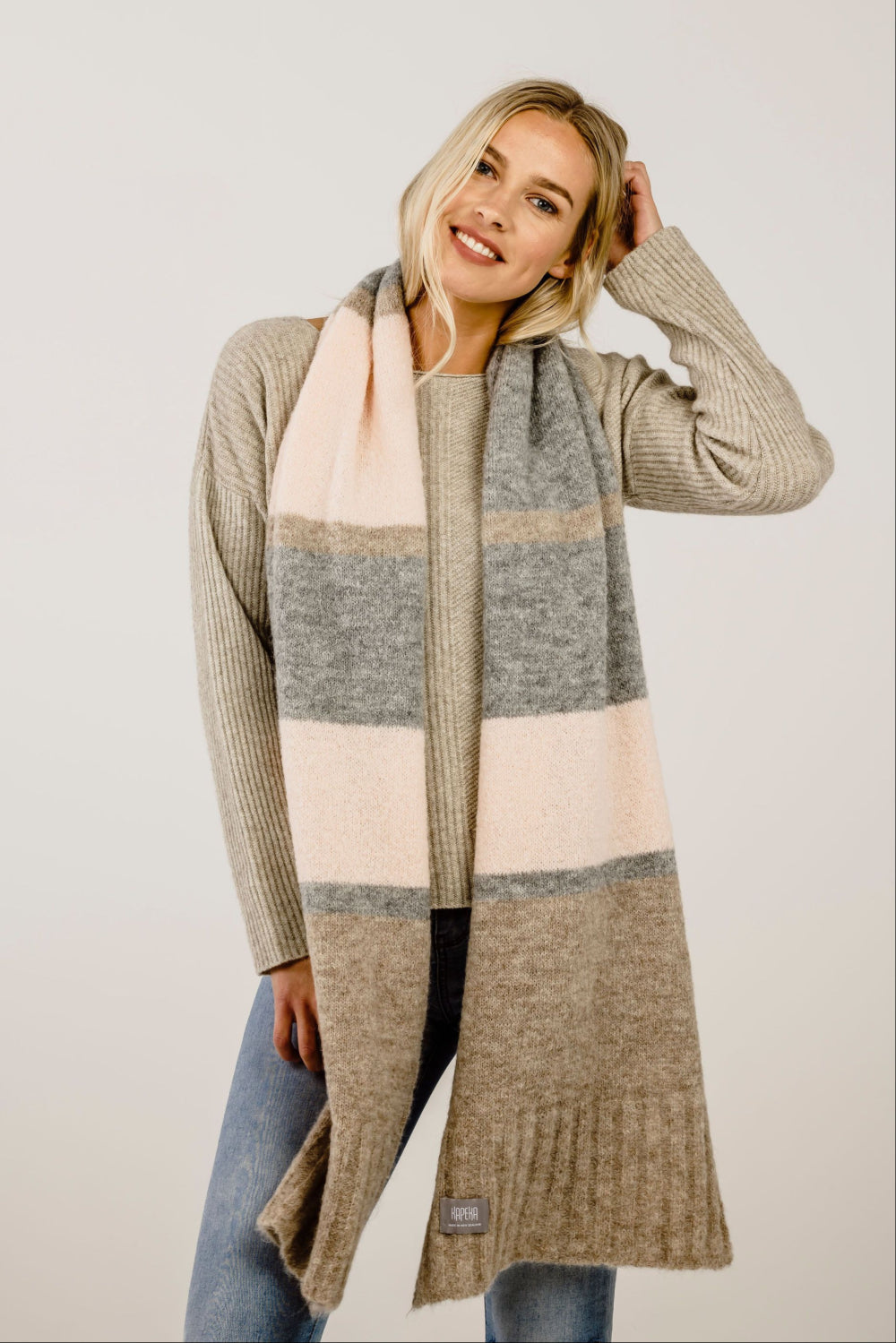 Woman wearing a long, patterned scarf with a neutral background
