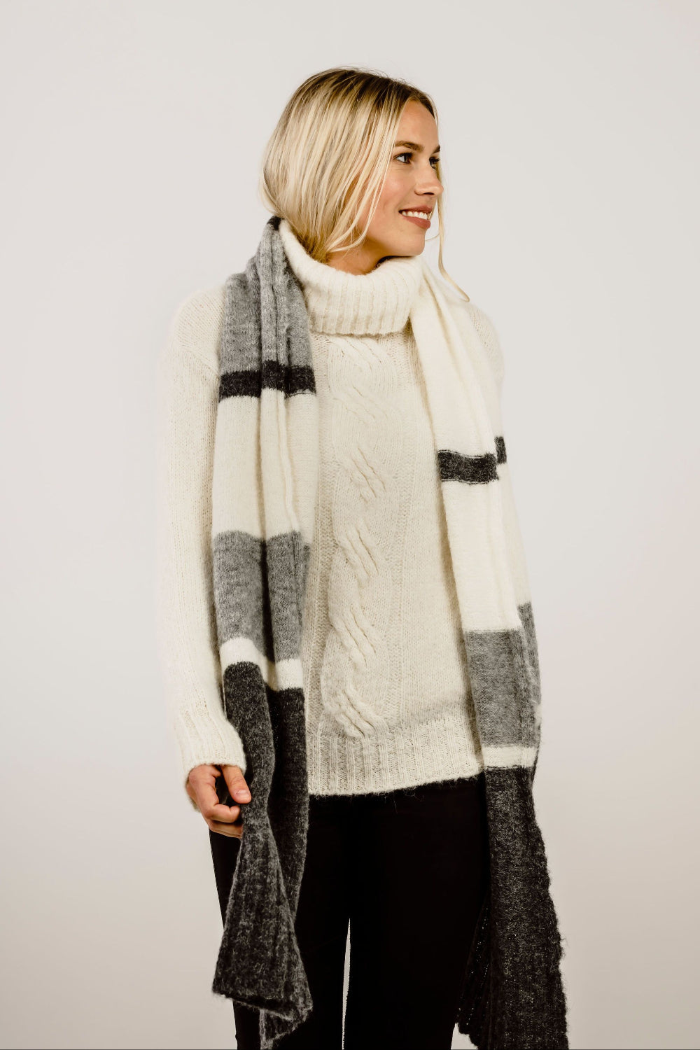 Woman wearing a long, plaid scarf with a plain background