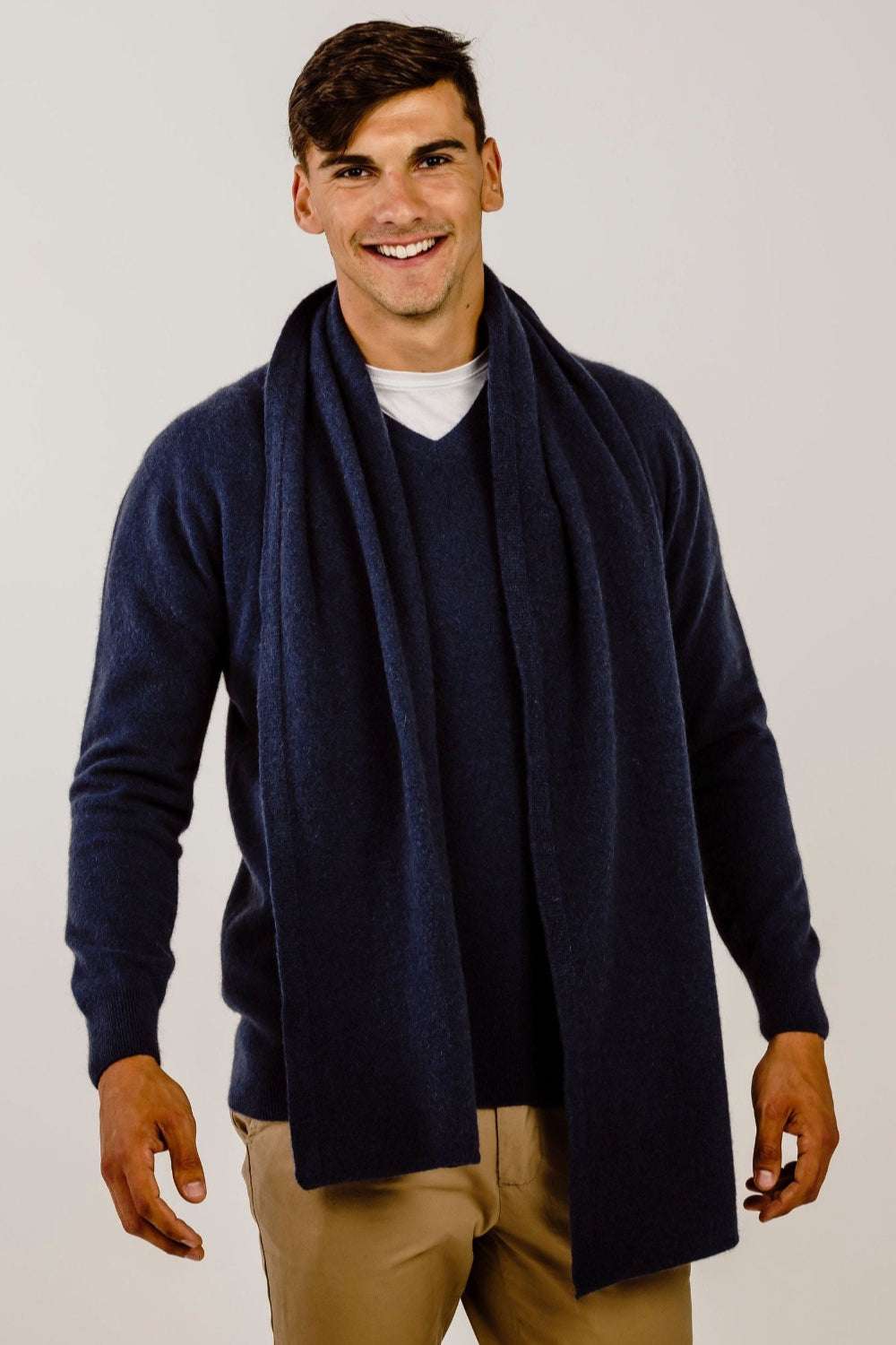 Man wearing a navy blue cardigan and scarf on a plain background