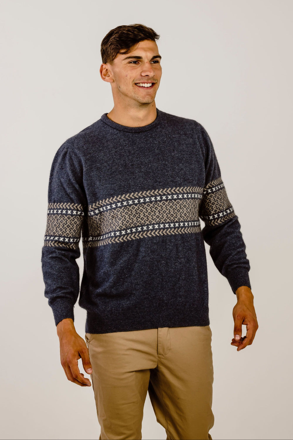 Man wearing a navy sweater with patterned sleeves against a plain background