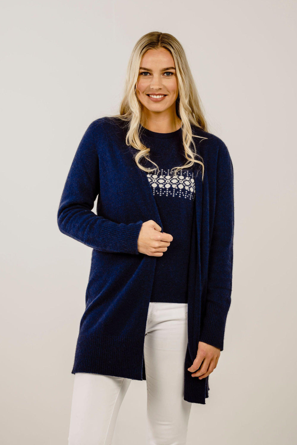 Woman wearing a navy blue cardigan with a white pattern on a plain background