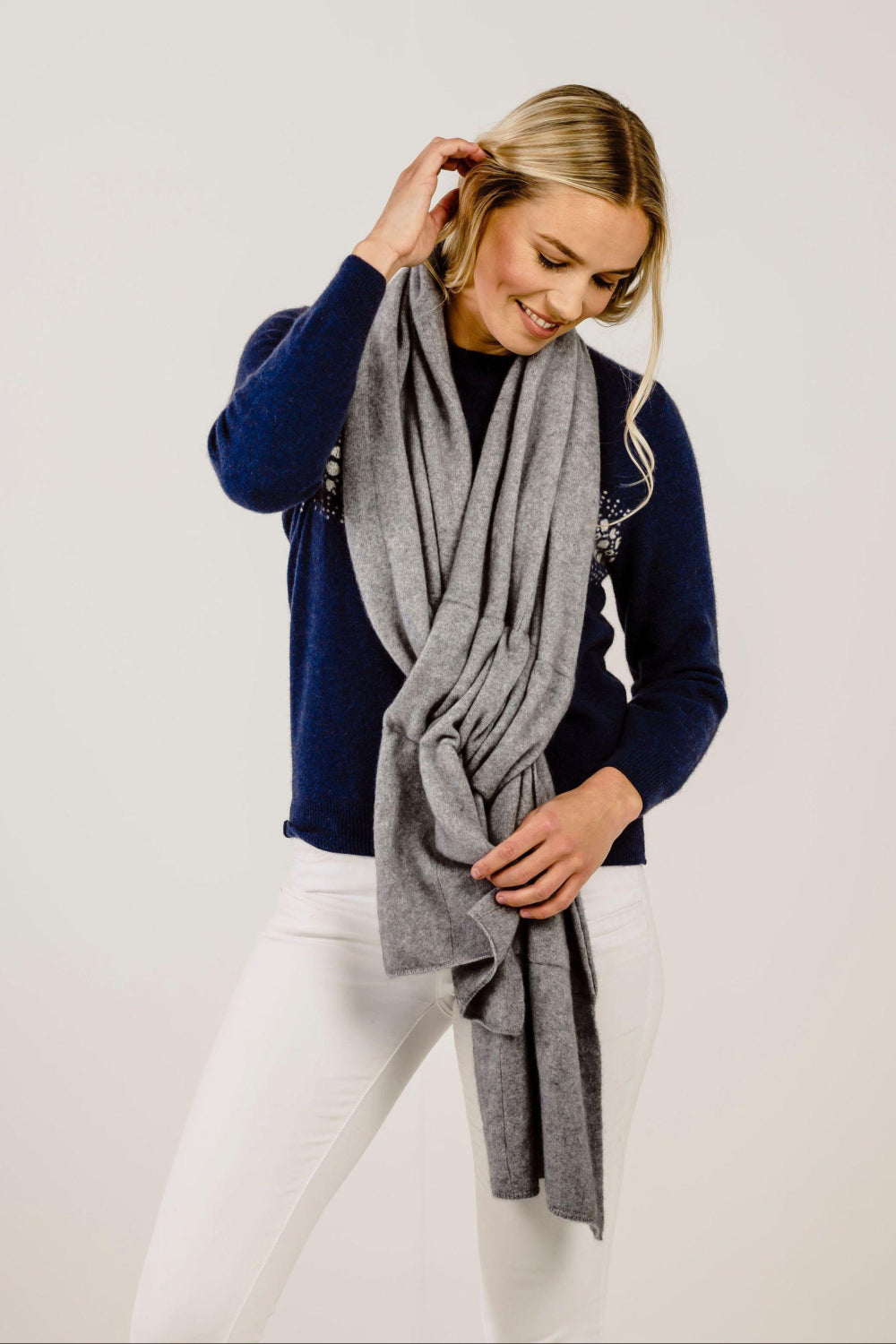 Woman wearing a gray scarf and navy sweater on a white background