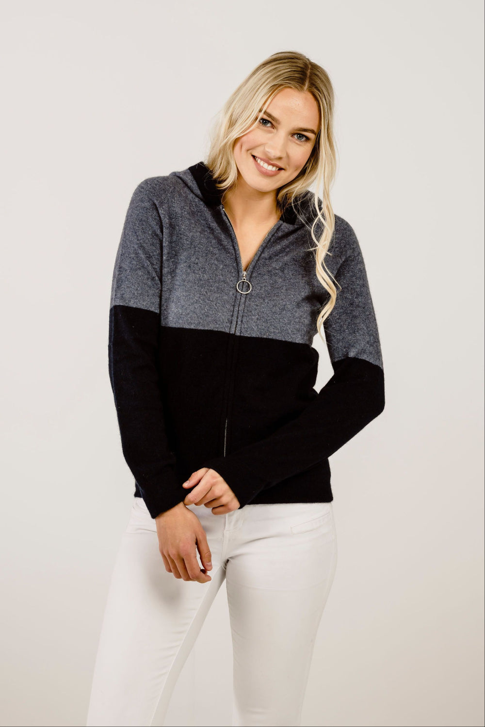 Woman wearing a black and gray color-blocked zip sweater on a plain background