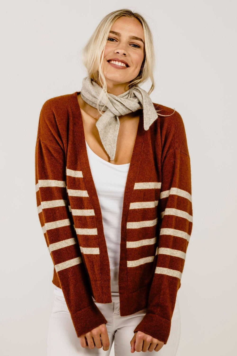 Woman wearing a stripe sweater and a beige scarf.