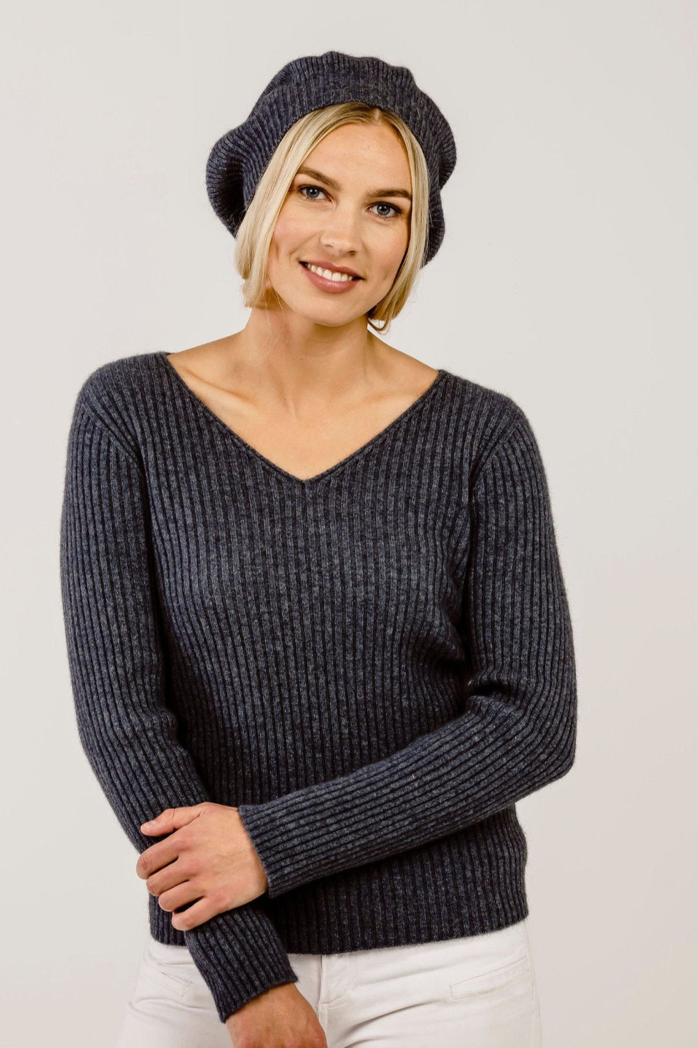 Woman wearing a dark gray ribbed sweater and matching beret hat against a plain background