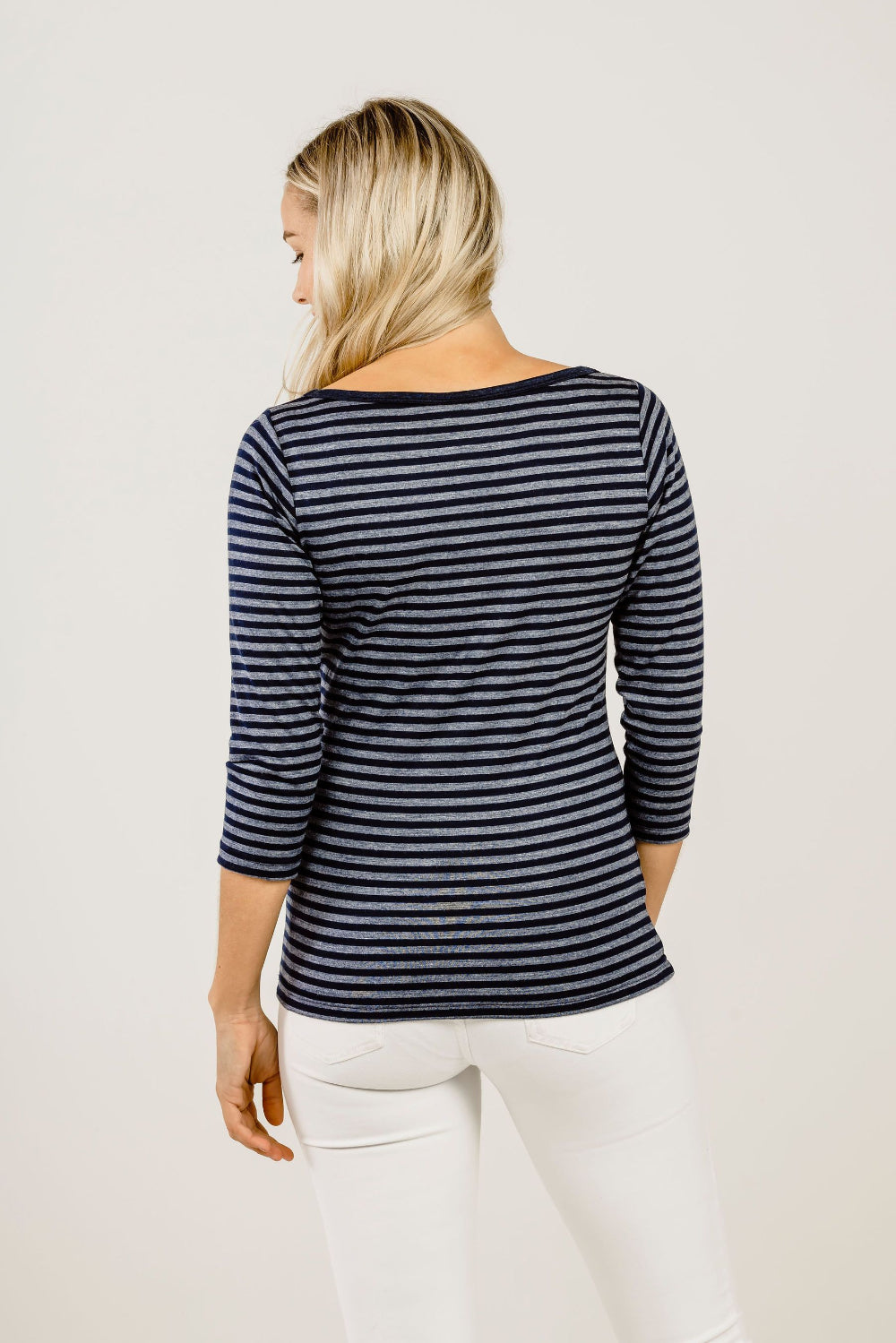 Woman wearing a black and white striped long-sleeve top on a plain background