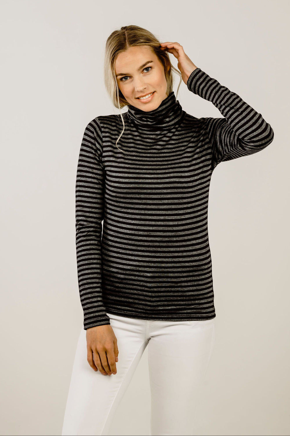 Woman wearing a black and gray striped turtleneck sweater against a plain background