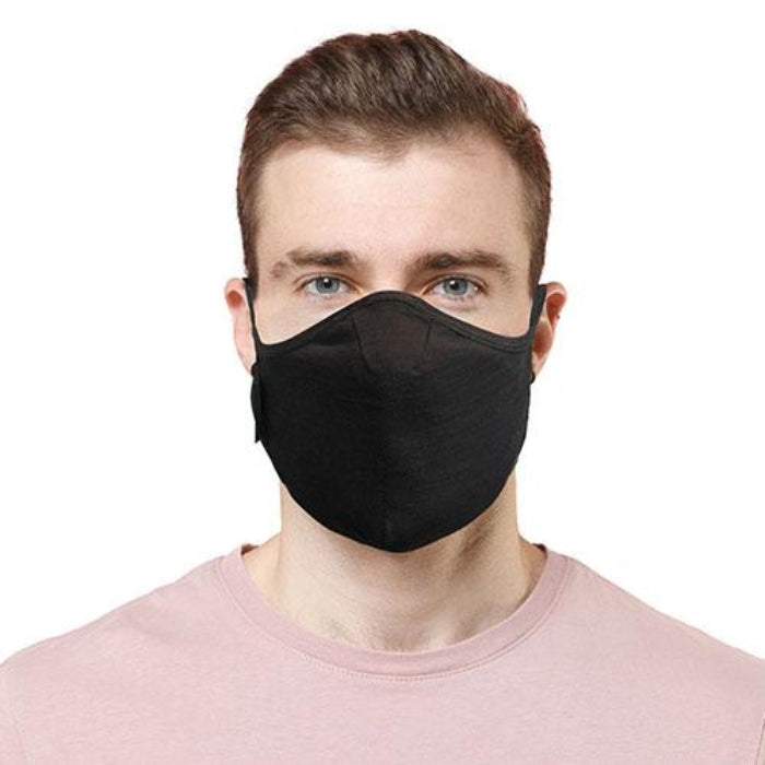 Man wearing ablack travel mask with adjustable elastic straps, made from merino soft & comfort next to skin, with a label showing 'Made in New Zealand', and highlighting features such as 100% breathable, adjustable elastic straps, and a machine washable filter. 