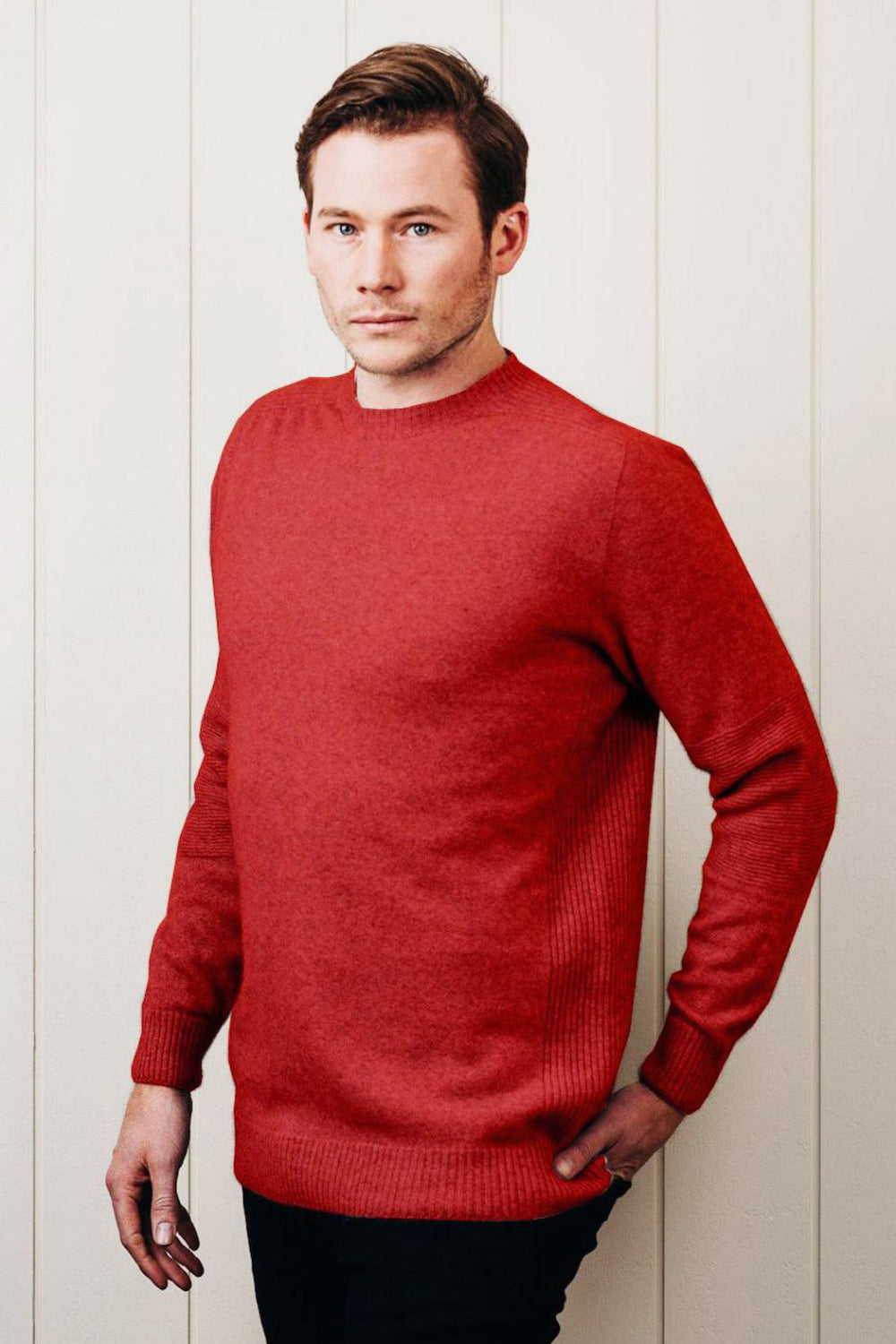 Man wearing a red sweater against a white wall