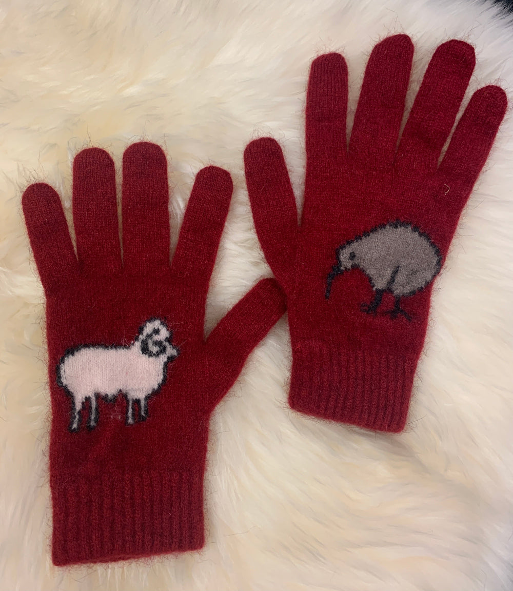 Red gloves with kiwi and sheep designs on a white fur background